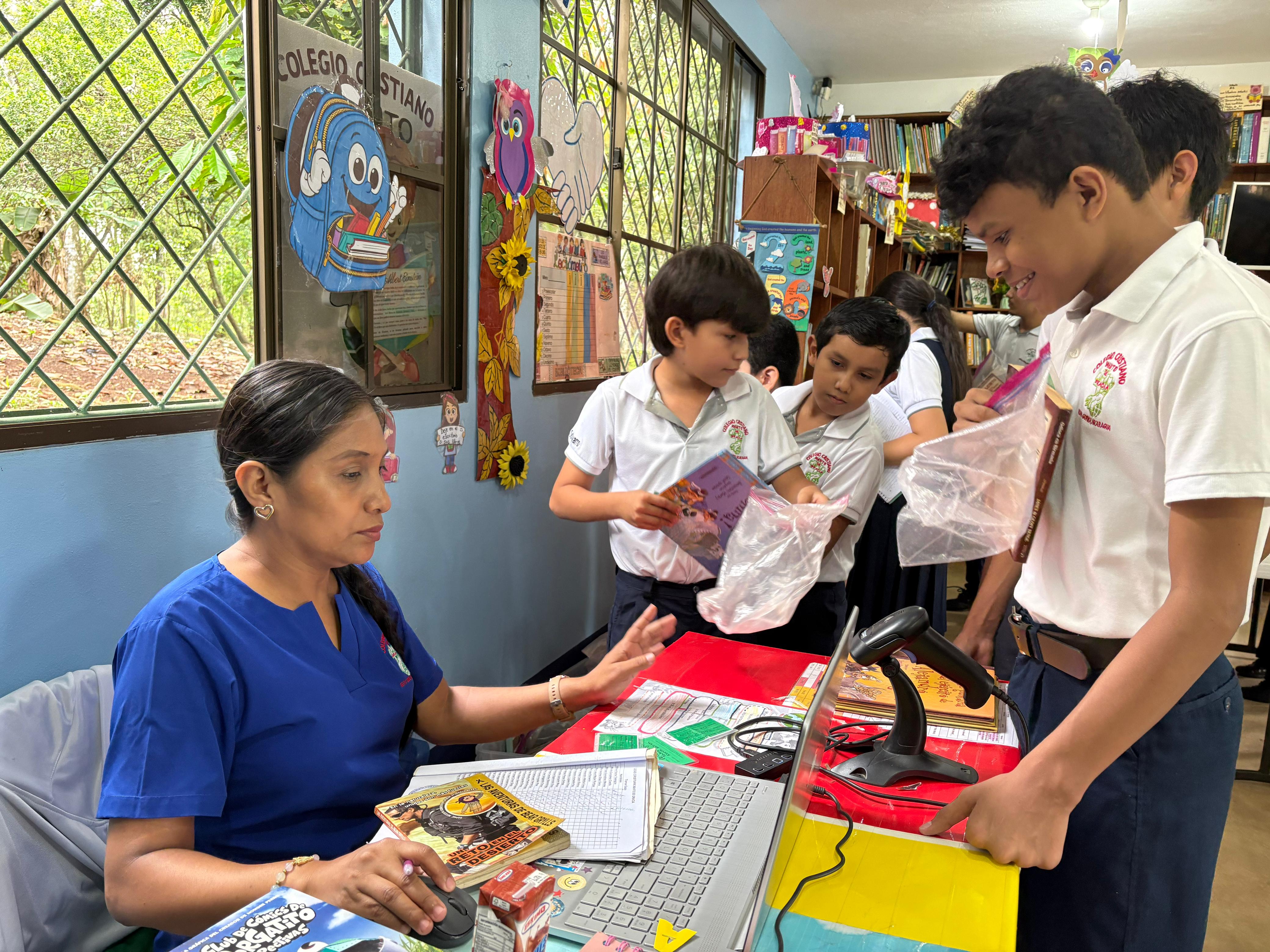 La bibliotecaria del colegio prestando libros a los estudiantes