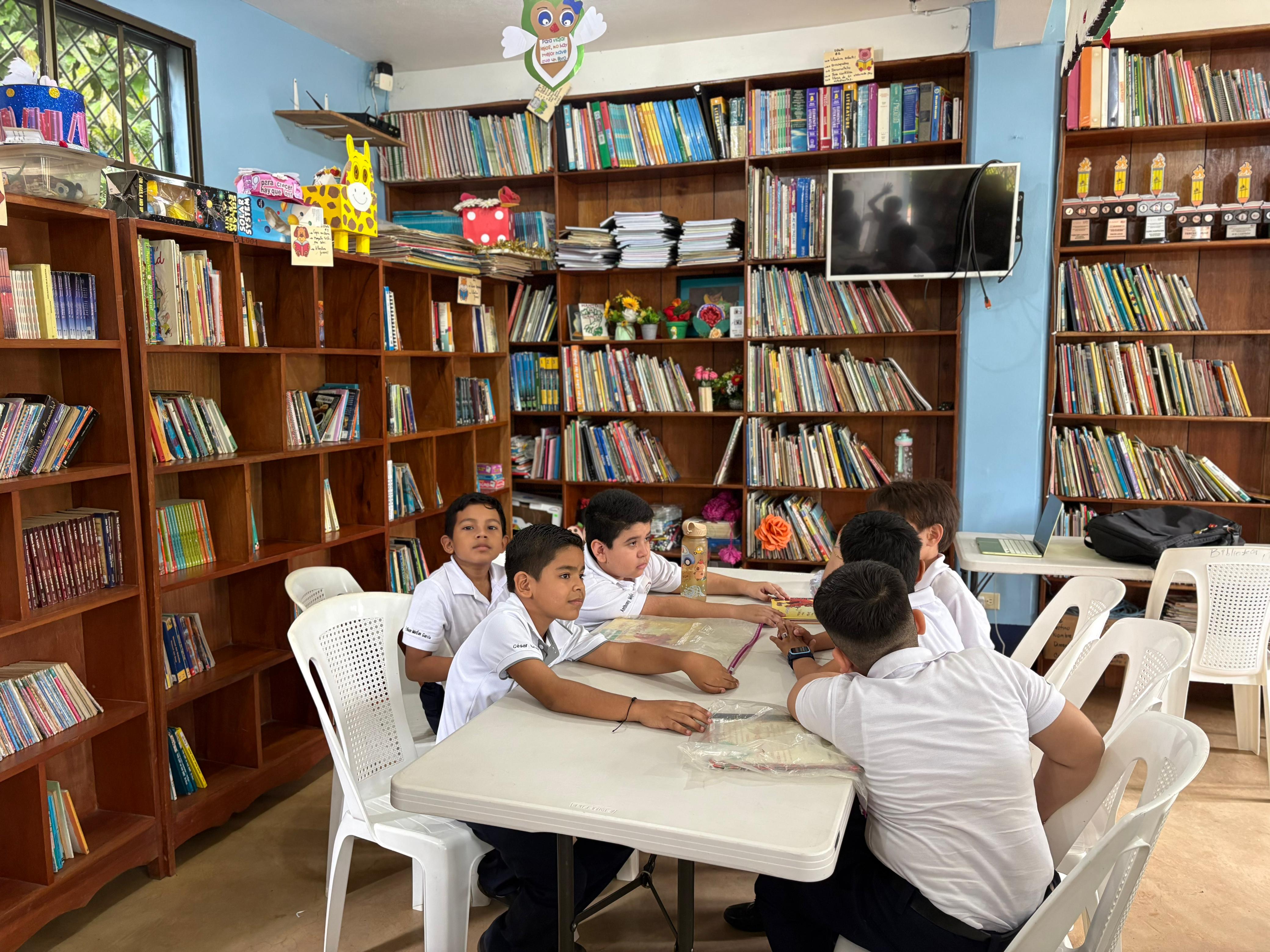 Estudiantes en una mesa dentro de la biblioteca del colegio